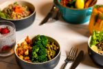 Delicious colorful bowls of salad and fresh beverages on a white table, perfect for healthy dining.