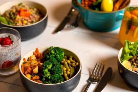 Delicious colorful bowls of salad and fresh beverages on a white table, perfect for healthy dining.