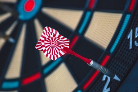 A dart striking the bullseye on a dartboard, showcasing precision and accuracy.